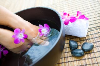 feet in foot spa bowl with orchids